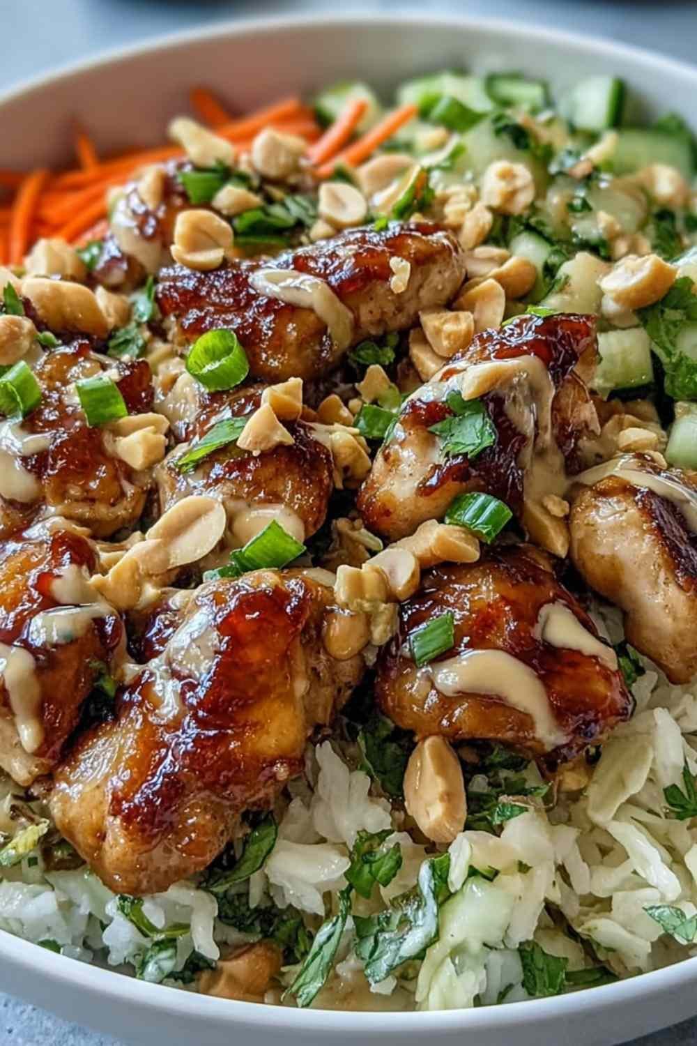 Peanut chicken protein bowl with coconut rice, sautéed chicken, red cabbage, carrots, and creamy Thai peanut sauce drizzle