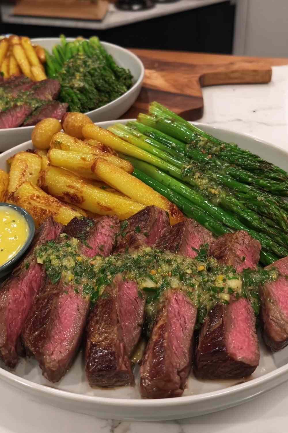 Sliced NY strip steak with truffle butter melting over the top, served with chimichurri fries and broccolini on a dinner plate
