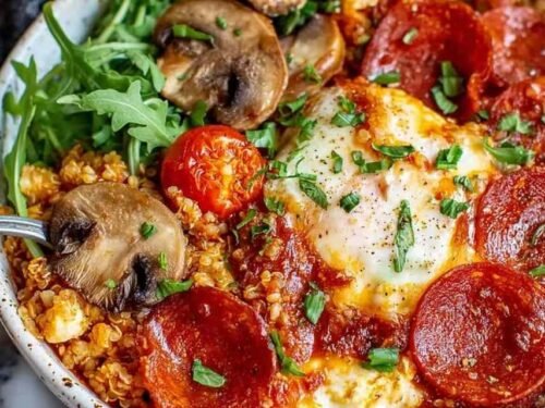 Pizza protein bowl with melted mozzarella, pepperoni, and fresh basil in an oven-safe bowl