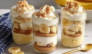 Protein banana pudding layered in glass jars with vanilla custard, crushed wafers, and fresh banana slices