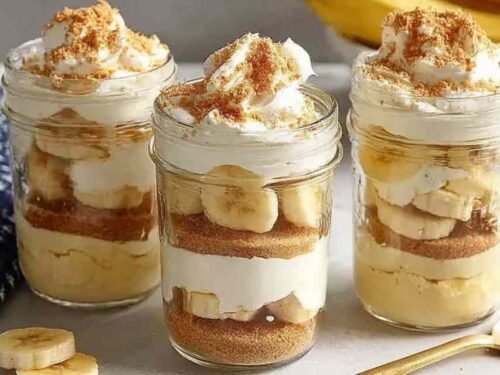 Protein banana pudding layered in glass jars with vanilla custard, crushed wafers, and fresh banana slices