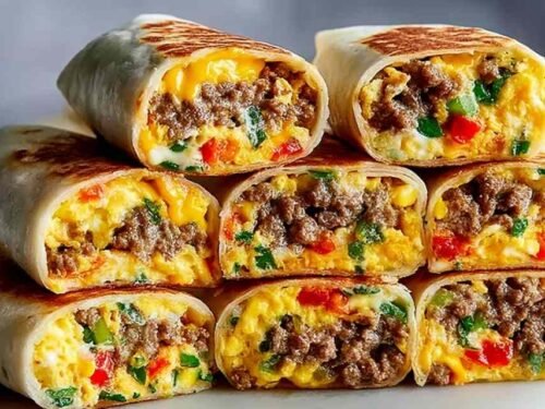 Cross-section of a protein-packed breakfast burrito showing roasted vegetables, seasoned ground meat, fluffy egg layer, and melted cheddar inside a flour tortilla