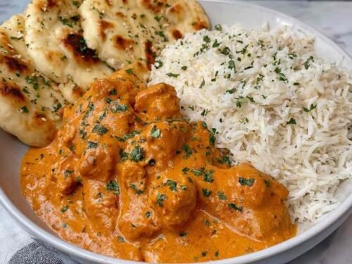 Quick easy homemade butter chicken simmering in a creamy orange tomato sauce garnished with fresh parsley