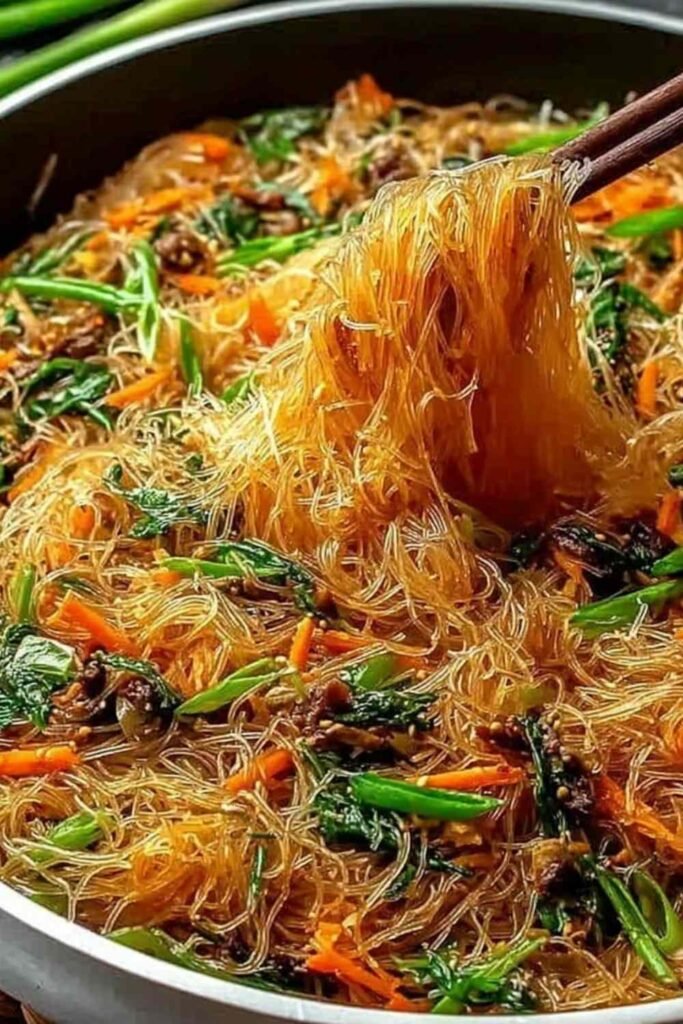 Rice Noodle Stir-Fry with colorful bell peppers, broccoli, carrots, and sesame seeds served in a white bowl
