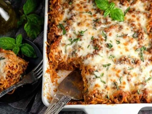 Southern baked spaghetti casserole in 9x13 baking dish with golden melted mozzarella and herb-seasoned meat sauce