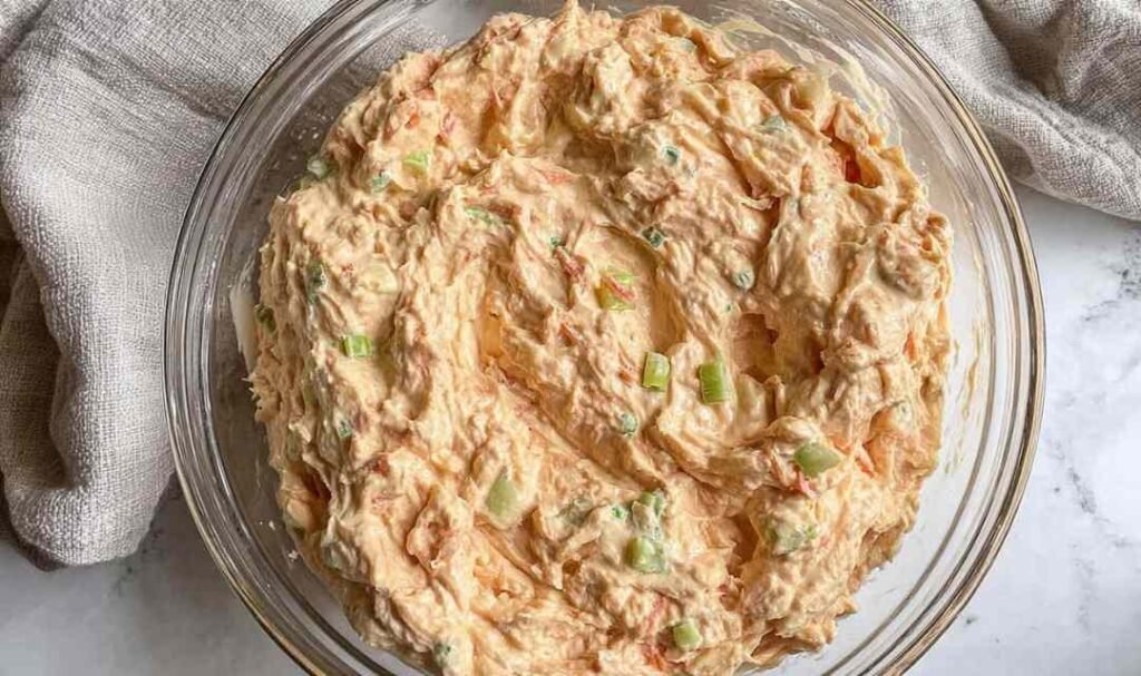 Buffalo tuna salad in a glass bowl with cottage cheese, celery, red onion, and Buffalo sauce ready to serve