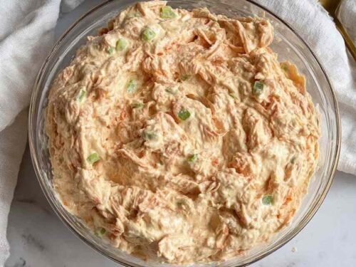 Buffalo tuna salad in a glass bowl with cottage cheese, celery, red onion, and Buffalo sauce ready to serve