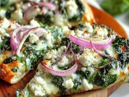 Spinach and Feta Flatbread Pizza with melted mozzarella, crumbled feta, wilted spinach, and golden crispy edges on parchment paper