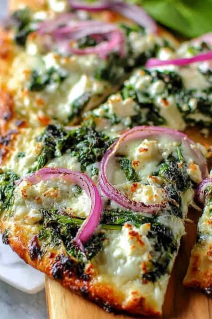 Spinach and Feta Flatbread Pizza with melted mozzarella, crumbled feta, wilted spinach, and golden crispy edges on parchment paper