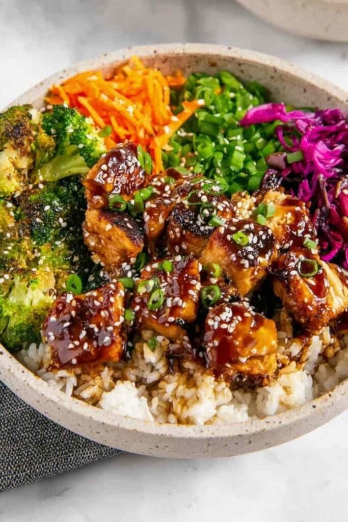 Sticky chicken bowls with glazed chicken thighs over jasmine rice and steamed broccoli garnished with sesame seeds and green onions