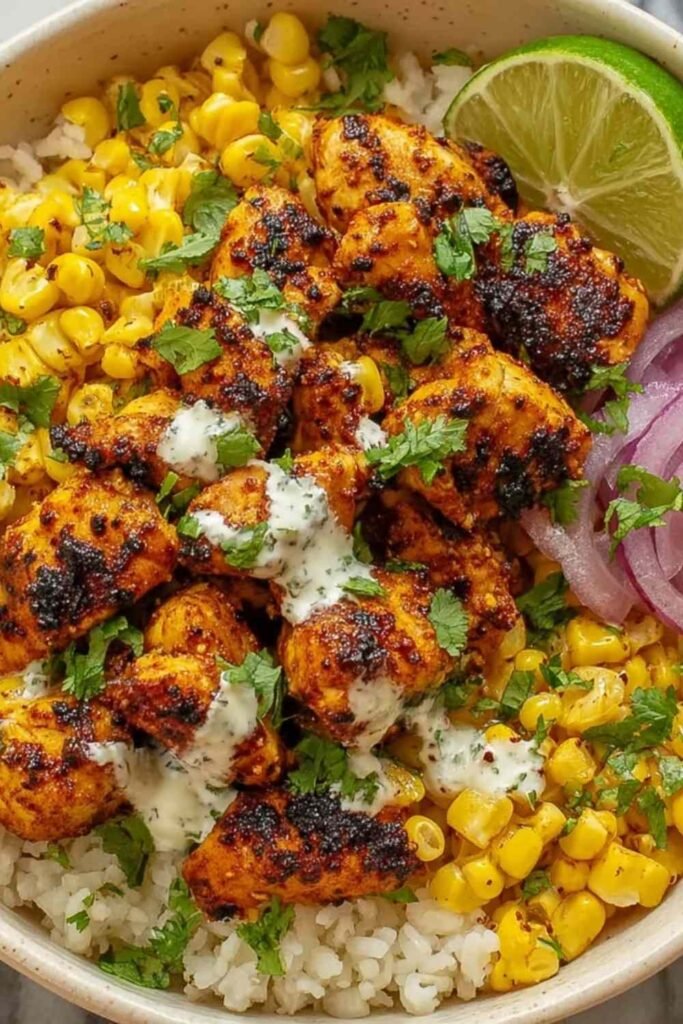 Street corn chicken rice bowl with charred corn, juicy chicken breast, diced avocado, Cotija cheese, and fresh cilantro over brown rice