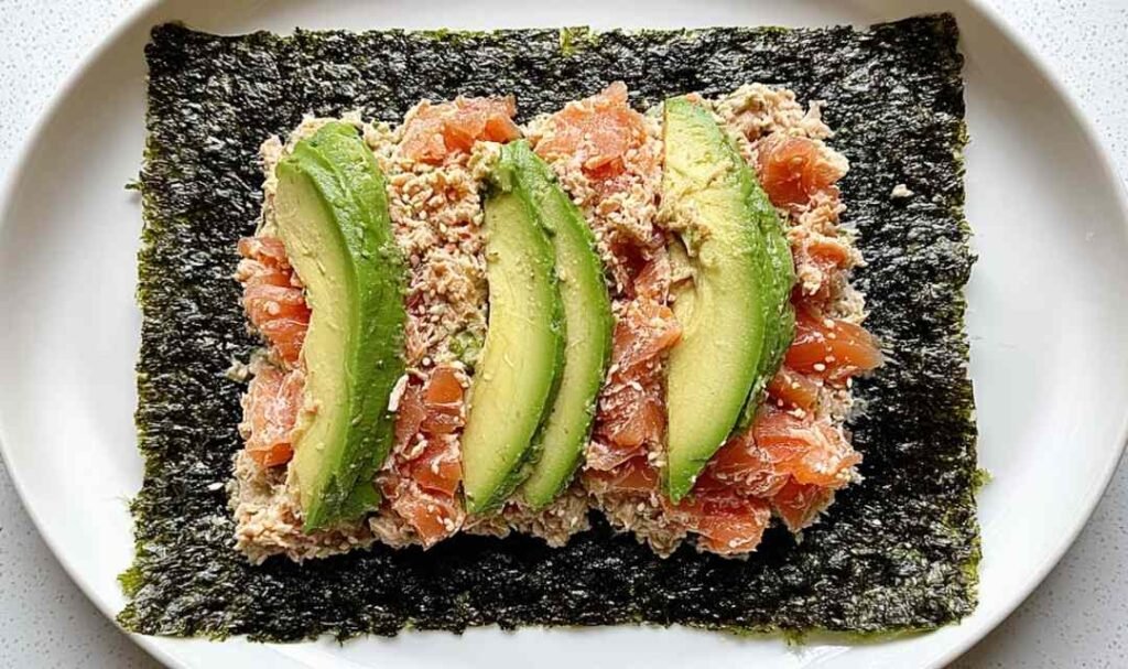 Tuna salad nori wraps with avocado slices and sesame seeds on a white plate