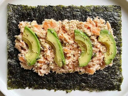 Tuna salad nori wraps with avocado slices and sesame seeds on a white plate