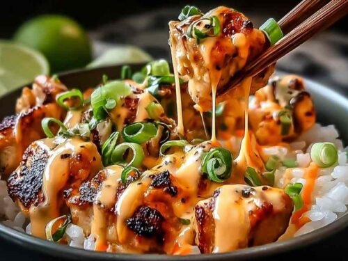 Sweet chili chicken bowl with coconut lime drizzle over jasmine rice with sesame seeds and lime wedge