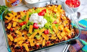 Walking Taco Casserole Walking Taco Casserole fresh from the oven in a 13x9 baking dish with melted Mexican cheese bubbling over seasoned ground beef, black beans, and crispy Frito corn chips