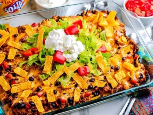 Walking Taco Casserole fresh from the oven in a 13x9 baking dish with melted Mexican cheese bubbling over seasoned ground beef, black beans, and crispy Frito corn chips