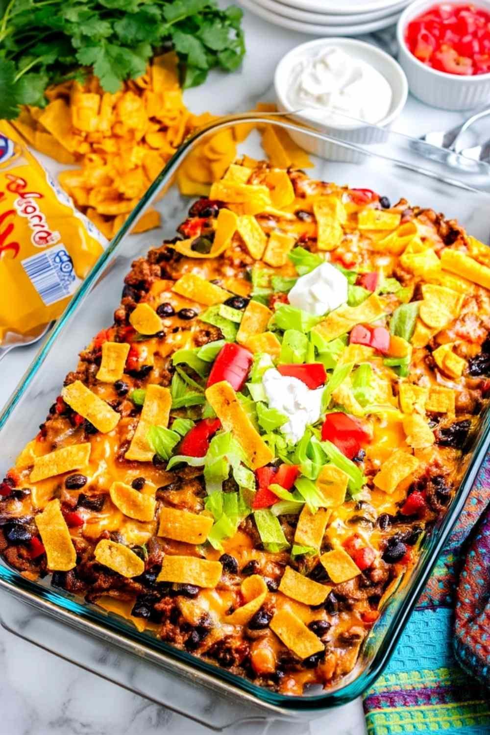 Walking Taco Casserole fresh from the oven in a 13x9 baking dish with melted Mexican cheese bubbling over seasoned ground beef, black beans, and crispy Frito corn chips