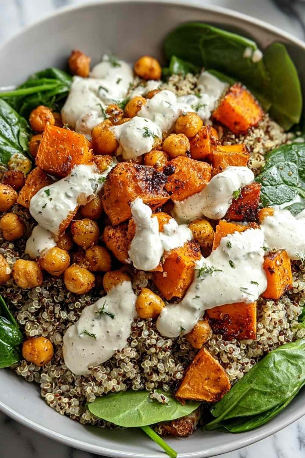 Anti-inflammatory glow bowl with quinoa, roasted sweet potatoes, crispy chickpeas, avocado, and tahini yogurt sauce