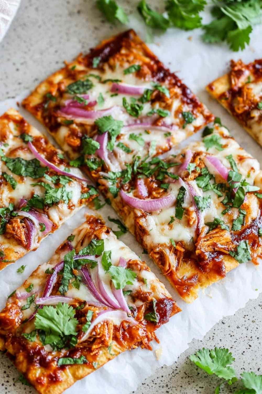 Freshly baked BBQ chicken crust pizza on a parchment-lined baking sheet, topped with melted mozzarella, crispy bacon, and red onion