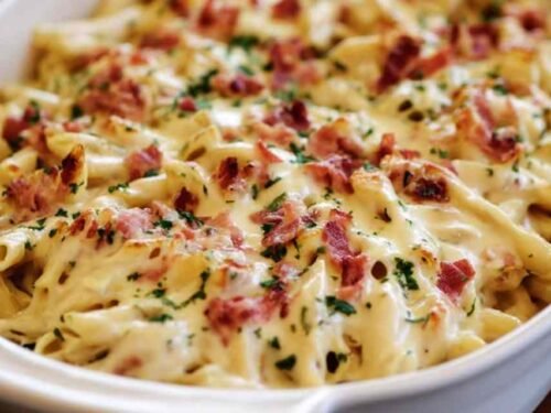 Chicken Bacon Ranch Baked Penne in a white baking dish with golden melted mozzarella and fresh parsley on top