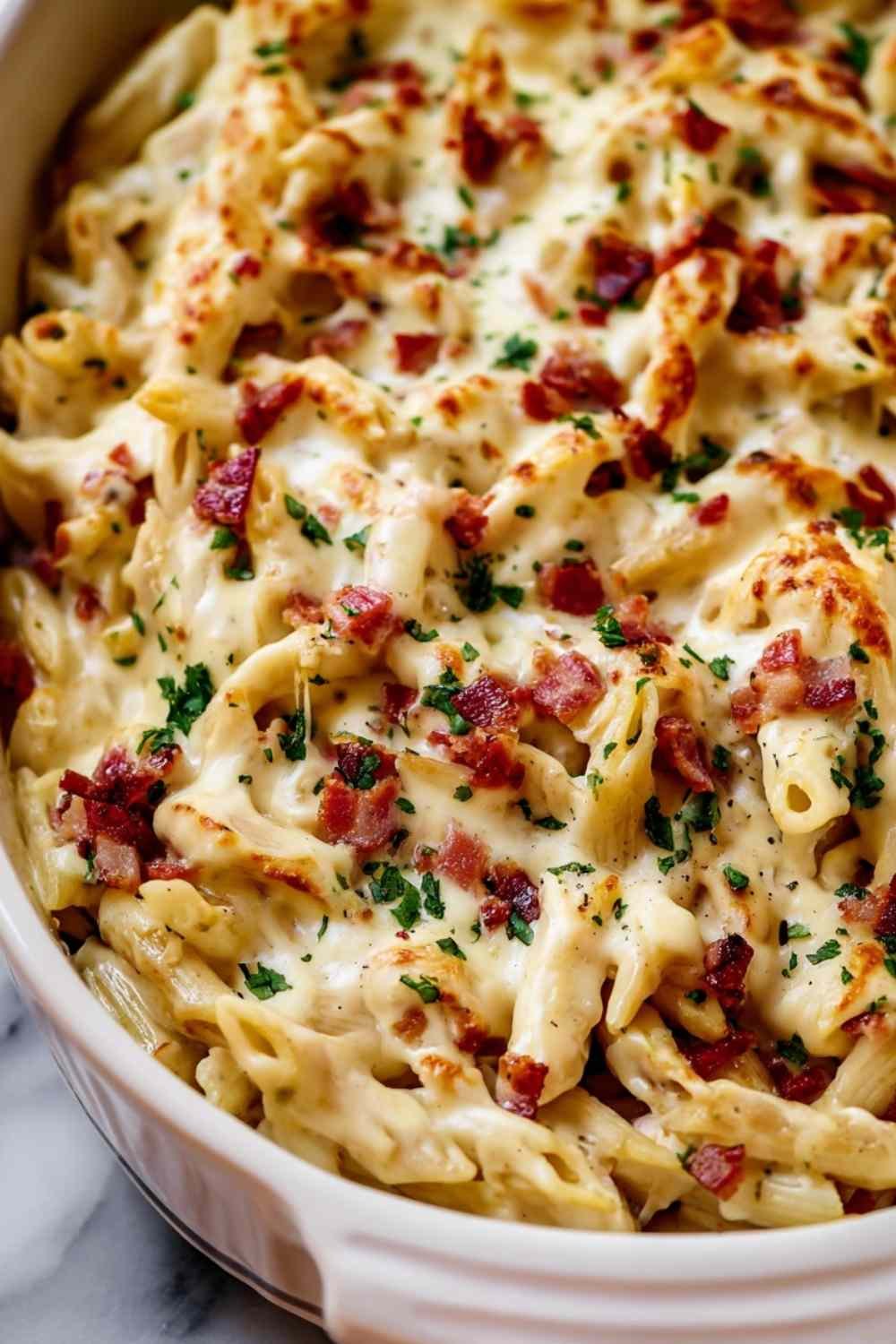 Chicken Bacon Ranch Baked Penne in a white baking dish with golden melted mozzarella and fresh parsley on top