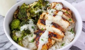 Chicken and broccoli bowls with creamy garlic sauce served over white rice in a white bowl with fresh parsley garnish