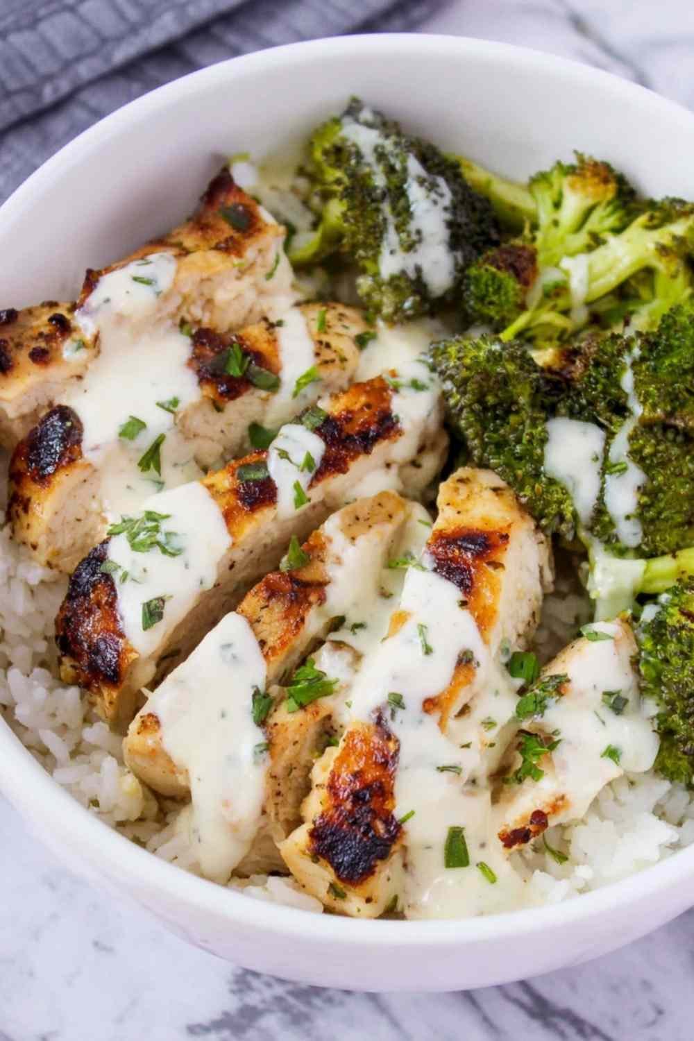 Chicken and broccoli bowls with creamy garlic sauce served over white rice in a white bowl with fresh parsley garnish