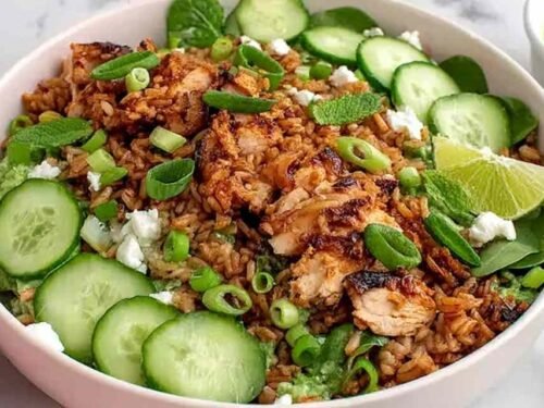 High protein crispy rice salad with golden chicken thighs, edamame, mint, and cilantro lime tahini dressing in a large serving bowl