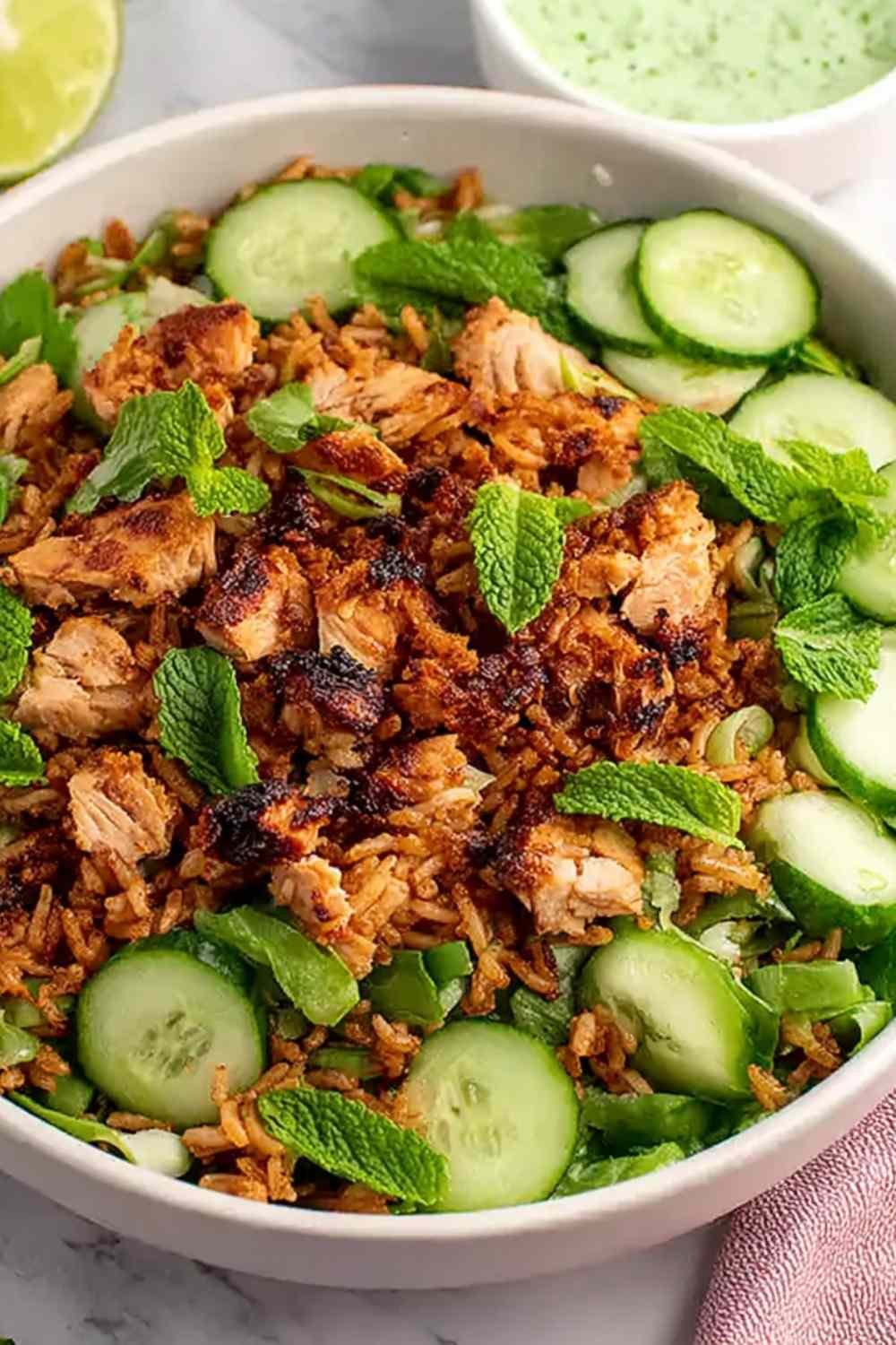 High protein crispy rice salad with golden chicken thighs, edamame, mint, and cilantro lime tahini dressing in a large serving bowl