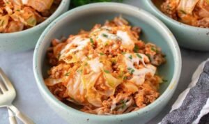 Overhead view of unstuffed cabbage rolls with ground beef, rice, and melted mozzarella in a white bowl