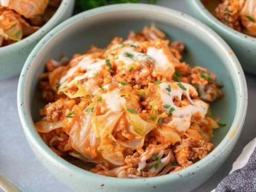 Overhead view of unstuffed cabbage rolls with ground beef, rice, and melted mozzarella in a white bowl