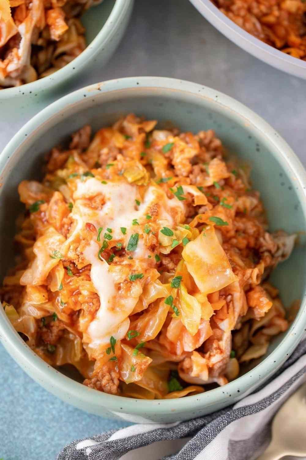 Overhead view of unstuffed cabbage rolls with ground beef, rice, and melted mozzarella in a white bowl