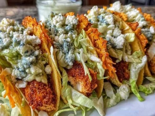 Dill Pickle Ranch Smash Chicken Tacos with crispy cheese laces, chopped pickles, and cottage cheese ranch sauce on a wooden board