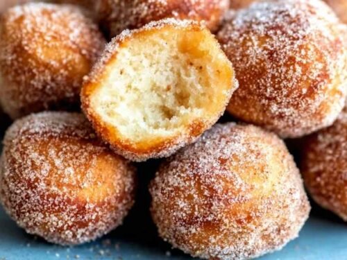 Walnut-sized dough balls for Churros Poppers being shaped on a wooden surface before frying in hot oil