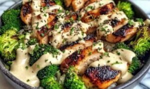 Grilled chicken and broccoli bowl with creamy garlic sauce served over brown rice in a white bowl