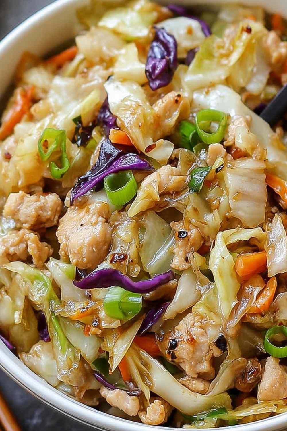 Egg roll bowls with chicken and cabbage topped with sesame seeds and green onions in a white bowl