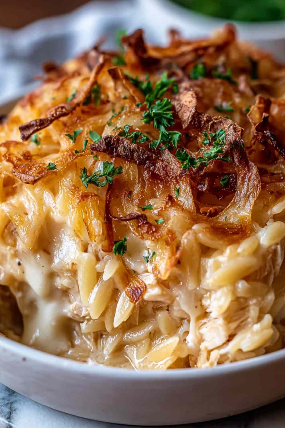Fresh ingredients for French Onion Chicken Orzo Casserole including orzo pasta, shredded chicken, yellow onions, mozzarella, and cream arranged on a wooden kitchen counter