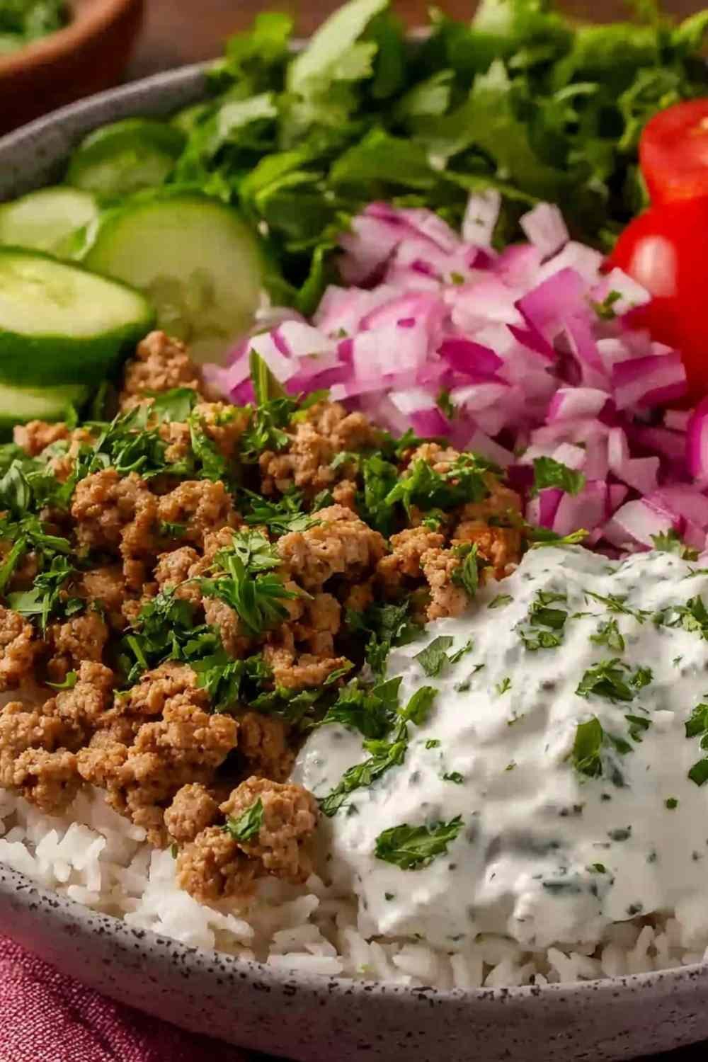 Assembled ground turkey bowl with jasmine rice, cucumber, grape tomatoes, red onion, and creamy lemon dill yogurt sauce