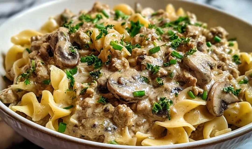 Creamy ground turkey stroganoff served over egg noodles garnished with fresh parsley in a white bowl