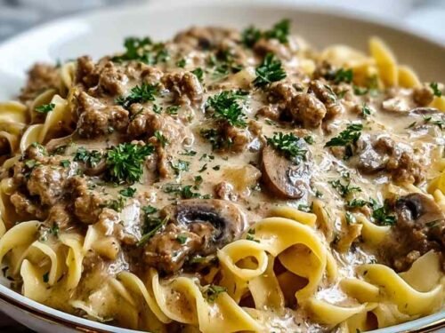 Creamy ground turkey stroganoff served over egg noodles garnished with fresh parsley in a white bowl