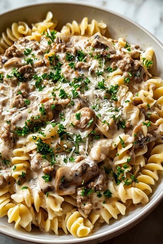 Creamy ground turkey stroganoff served over egg noodles garnished with fresh parsley in a white bowl