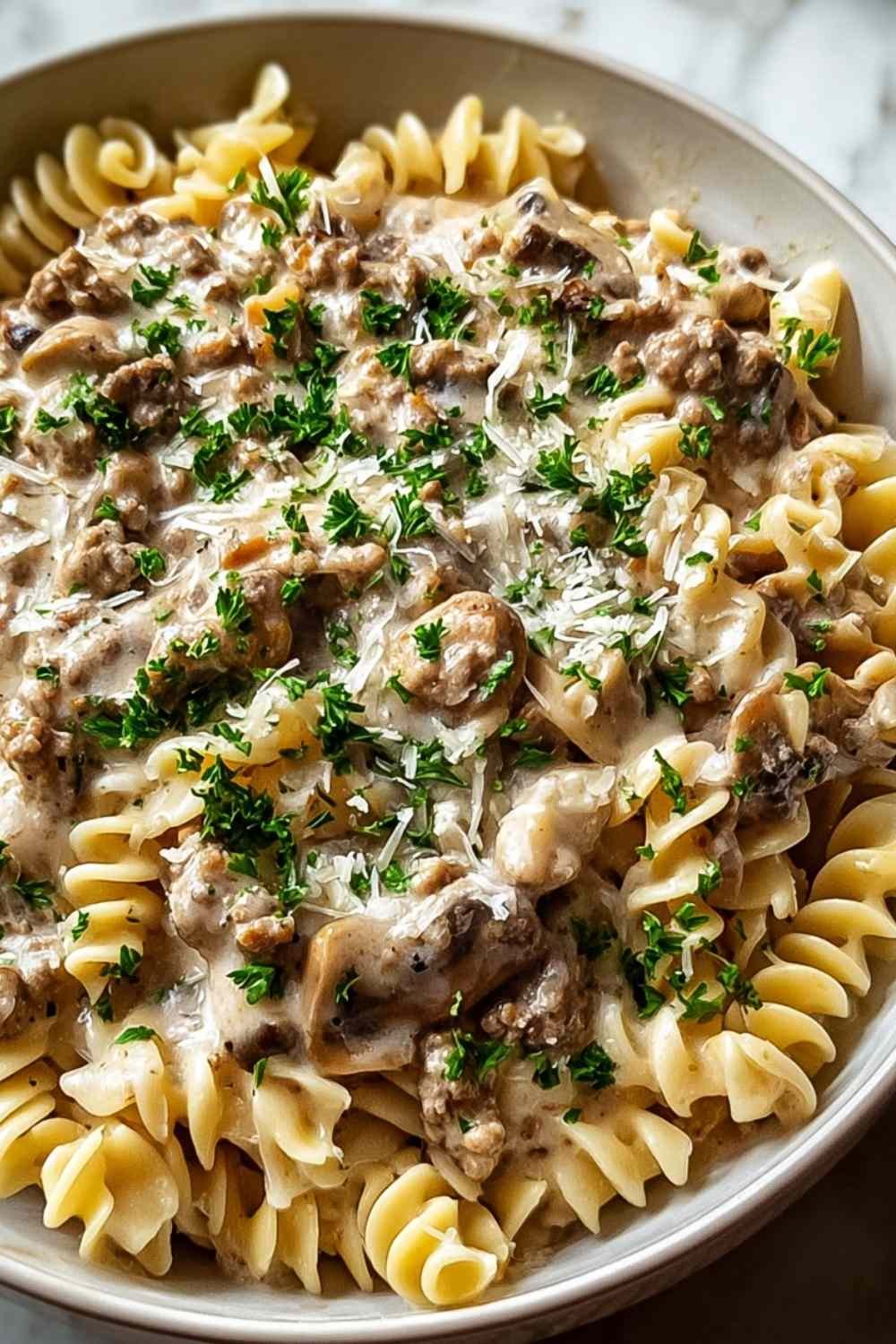 Creamy ground turkey stroganoff served over egg noodles garnished with fresh parsley in a white bowl