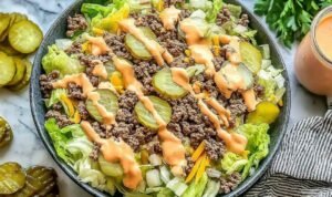 High Protein Cheeseburger Bowl (Big Mac Style) High protein cheeseburger bowl with seasoned ground beef, chopped lettuce, diced pickles, shredded cheddar, and creamy Big Mac sauce