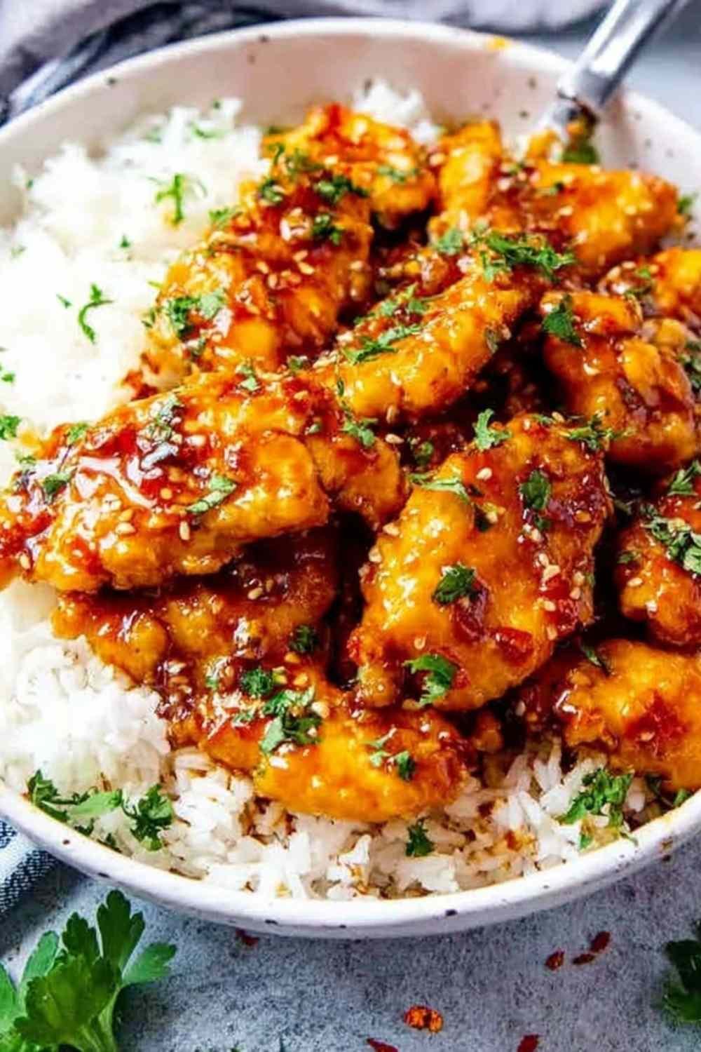 Close-up of honey garlic chicken thighs in a skillet with glossy sauce, garnished with parsley and chili flakes