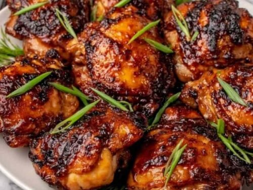 Roasted miso chicken thighs on a white serving platter garnished with sliced green onions