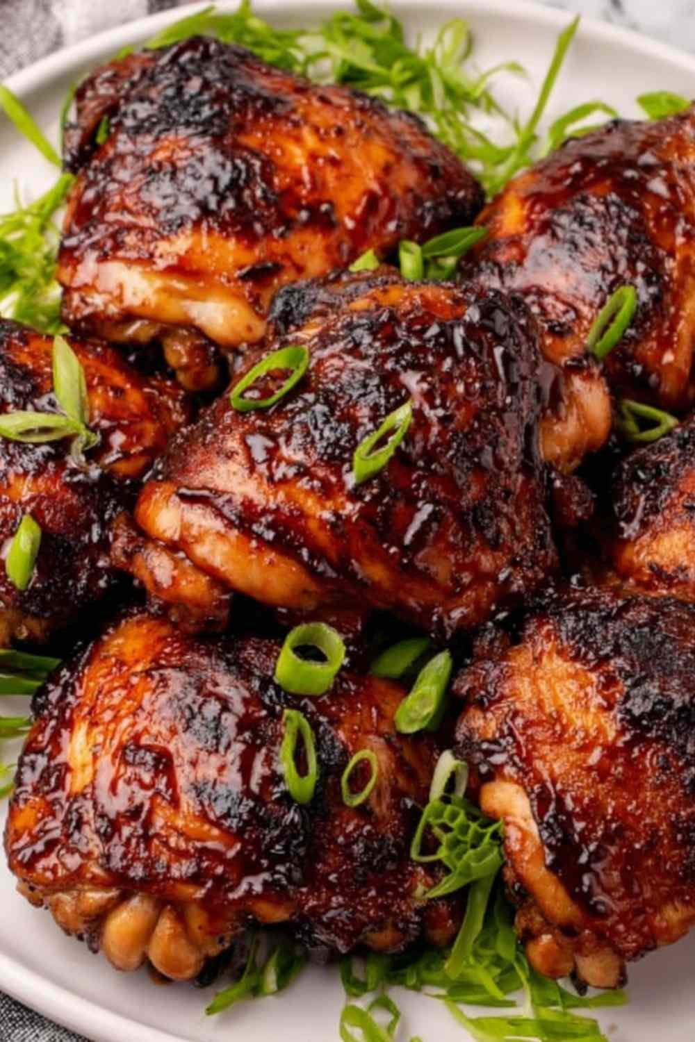 Roasted miso chicken thighs on a white serving platter garnished with sliced green onions