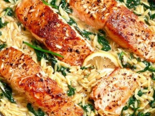 One skillet salmon with lemon orzo served in a large nonstick pan with wilted spinach, Parmesan, and chili flakes