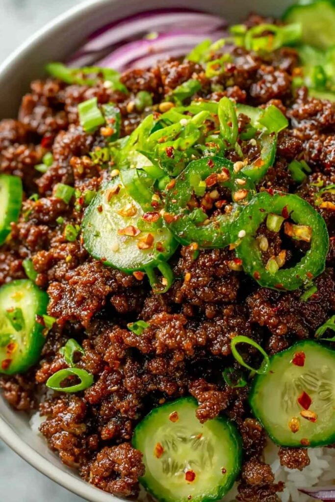 Spicy keto Korean ground beef in a bowl with gochujang sauce served alongside a fresh cucumber salad with sesame seeds