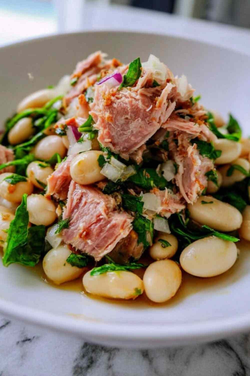 Tuna and white bean salad with lemon vinaigrette served in a large bowl with fresh parsley and red onion