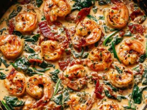 Tuscan shrimp in a creamy garlic sauce with spinach, artichokes, and sun-dried tomatoes in a large skillet